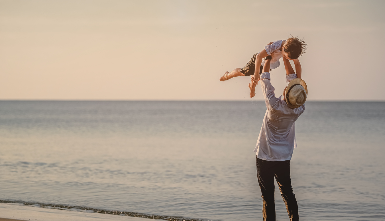 Joyful Dad holding his son at the beach for Father's Day