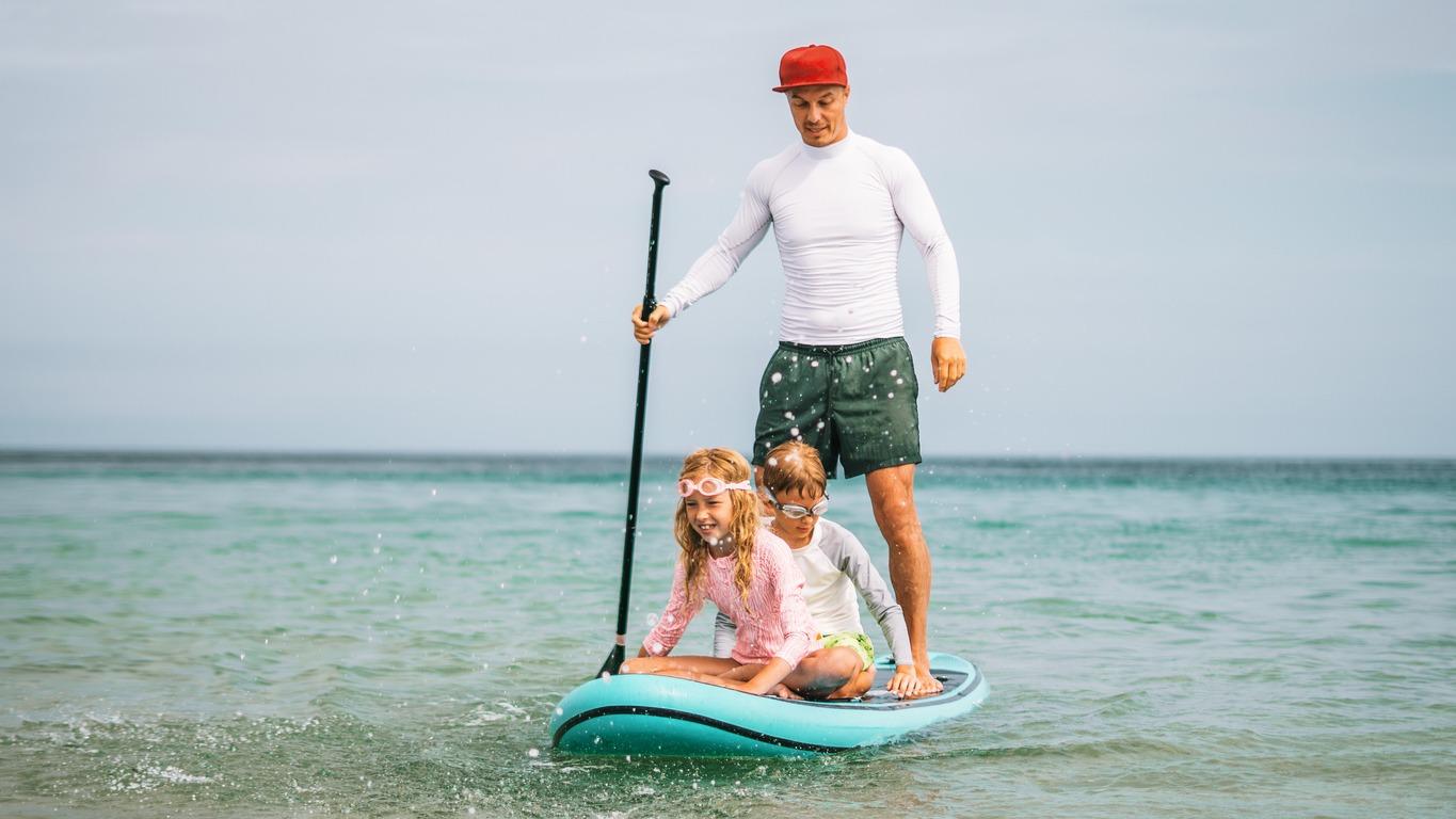 A Dad and two of his kids paddleboarding together for Father's Day.